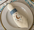 Elegant table setting with decorative napkins, cutlery, and tableware on a patterned tablecloth.